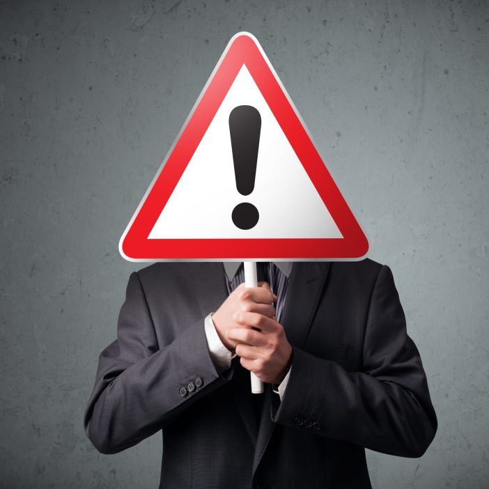Businessman,Holding,A,Red,Traffic,Triangle,Warning,Sign,In,Front